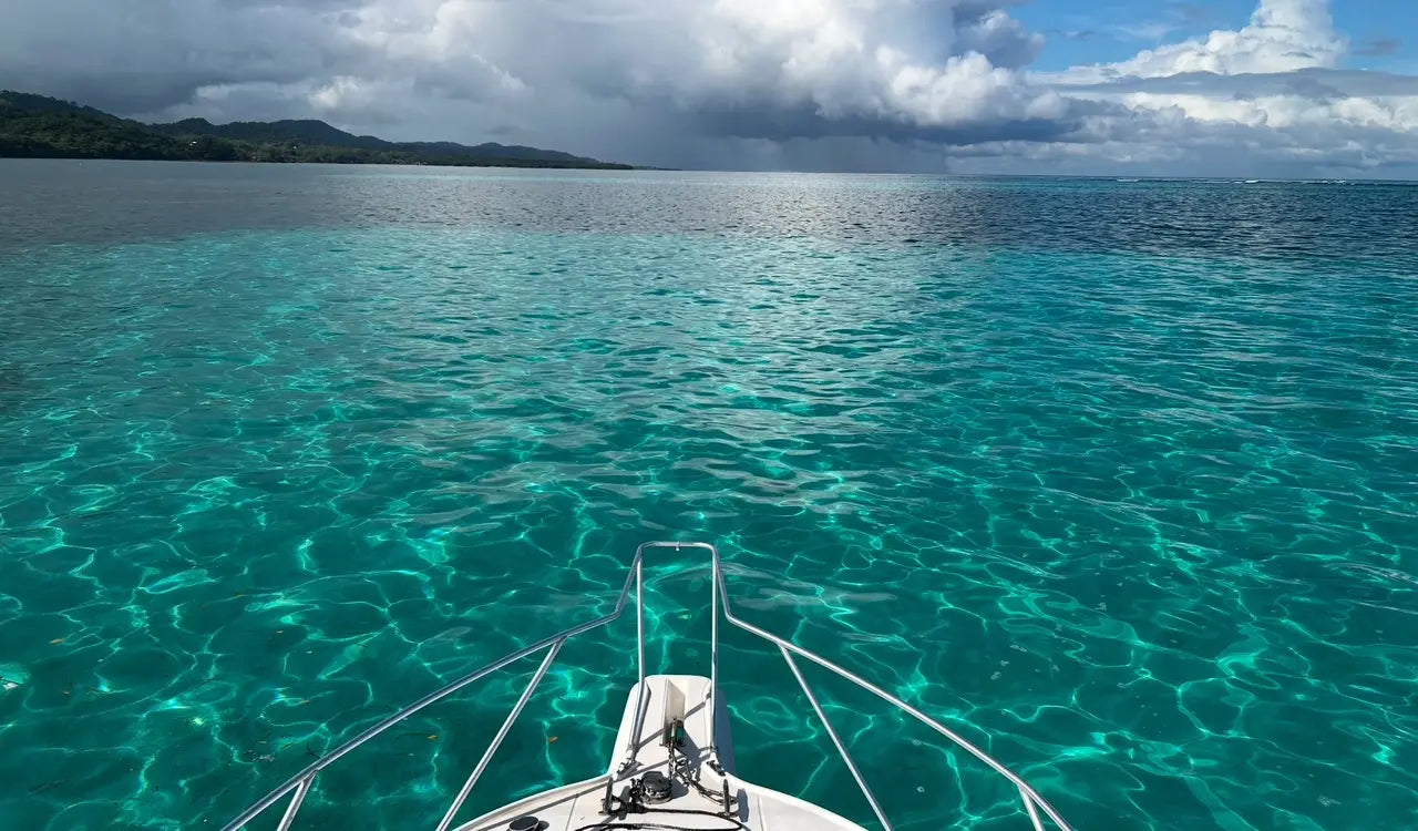 Boat on clear turquoise water with a cloudy sky