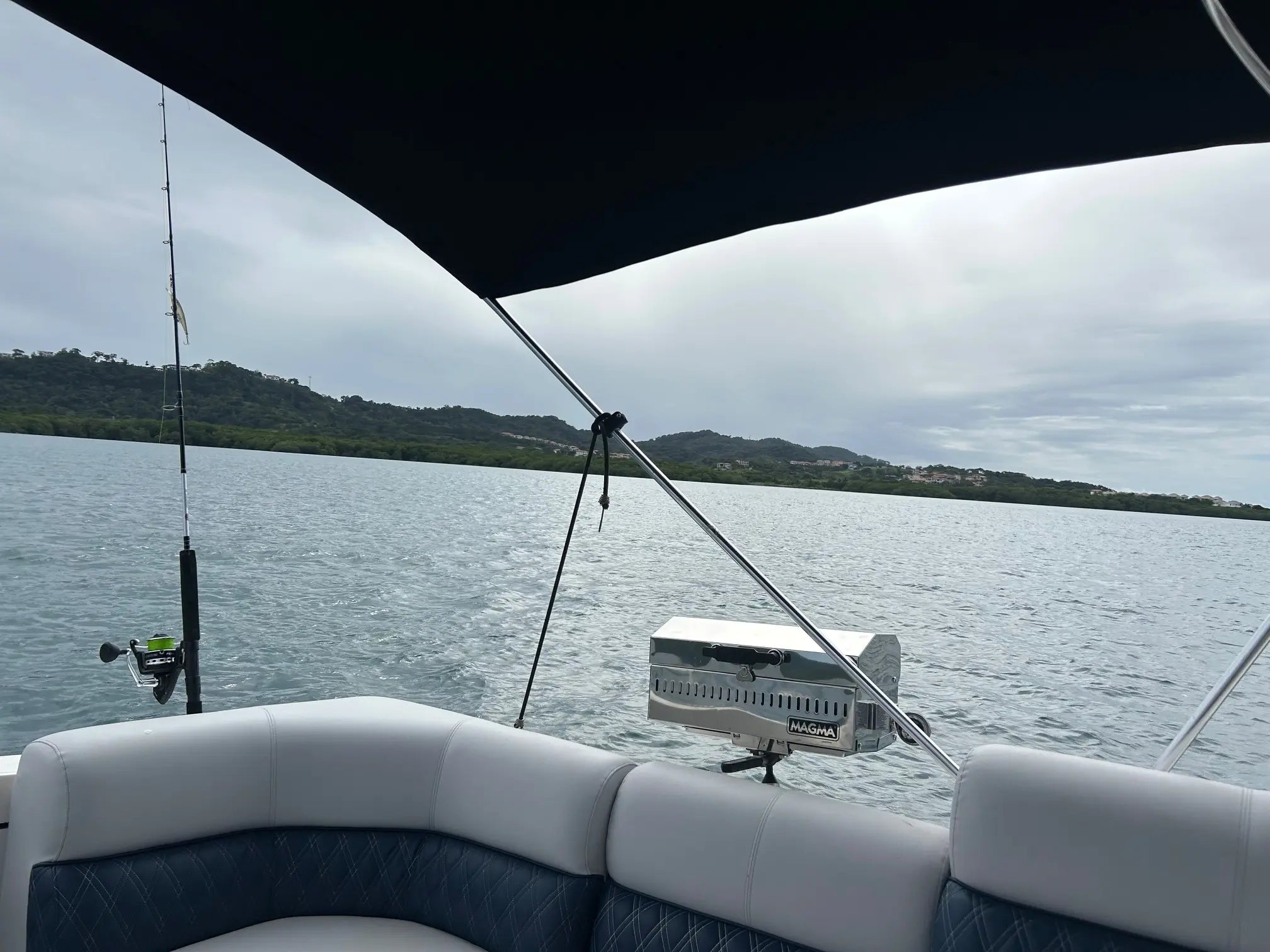 View from inside a boat on a body of water with fishing rod and seat visible